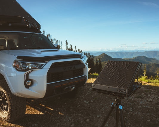 Tuff Mount for Starlink Mini shown on a tripod in front of vehicle with view of mountain in the background. 