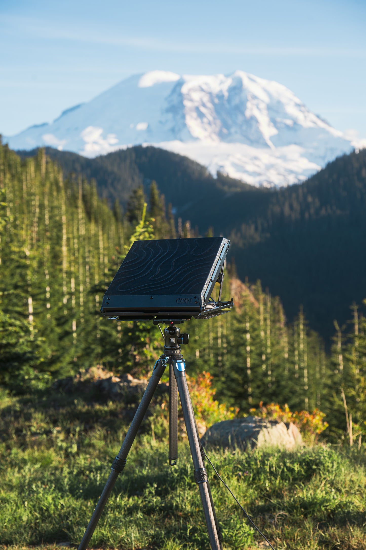 Tuff Mount for Starlink Mini shown on a Tripod using the Tripod Adapter in the wilderness with mountain in the background. 